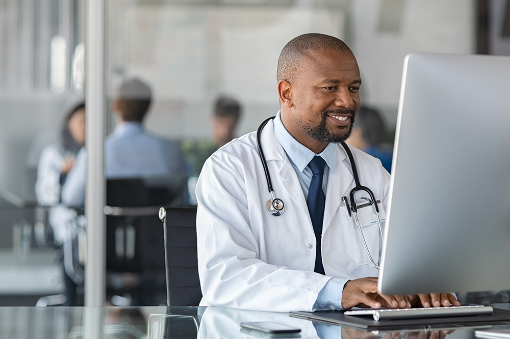 Doctor with white coat and stethoscope working at a laptop computer